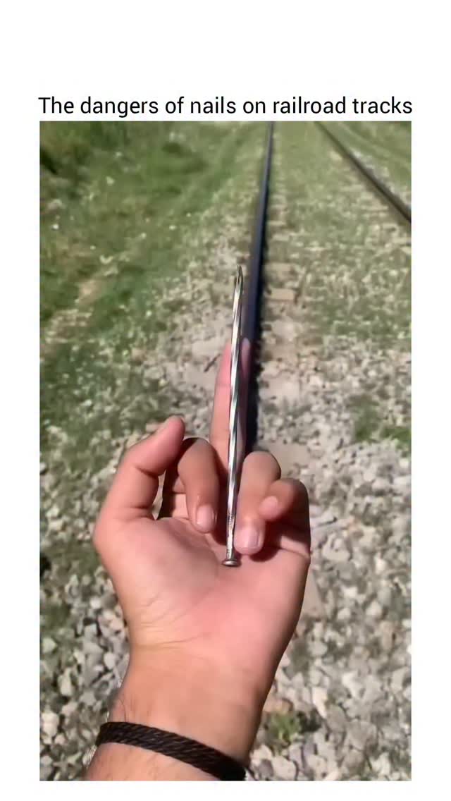 The video opens with a close-up of a hand placing a long, thin metal object across a railway track, …